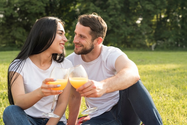 Free photo couple having orange juice on picnic blanket