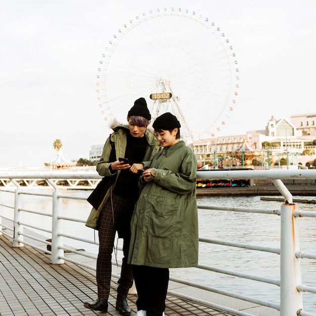 Free Photo couple holding devices outdoors