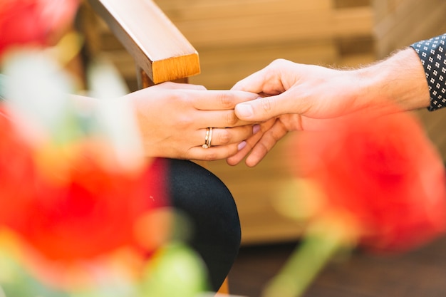 Free photo couple holding hands in front of blurred rose