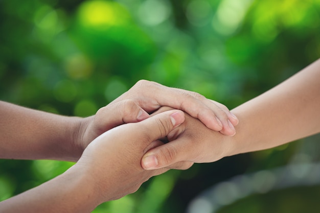 Couple holding hands in green meadow.