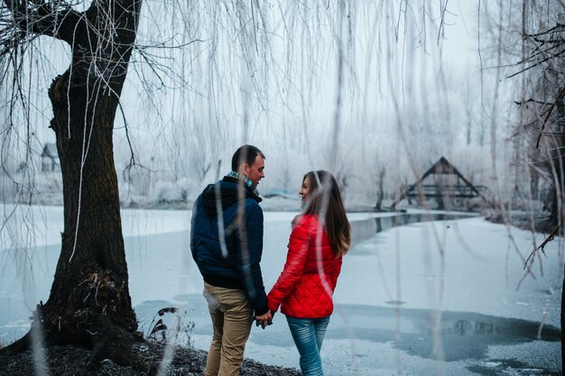 Couple holding hands under a snowy tree