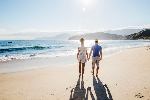 Couple holding hands and walking at the beach