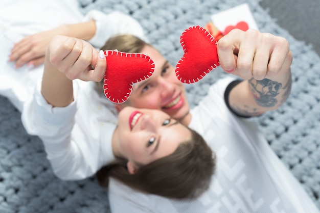 Free photo couple holding red toy hearts in hands