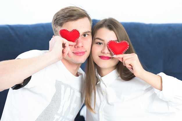 Free Photo couple holding small toy hearts at faces