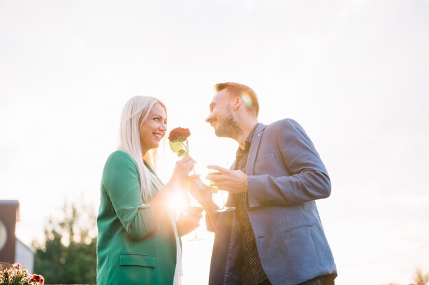 Couple holding wineglasses proposing to her girlfriend by giving red rose