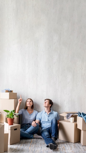 Couple at home packing to move out and pointing up