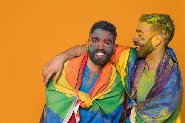 Couple of homosexual men covered by LGBT flag and colorful painted