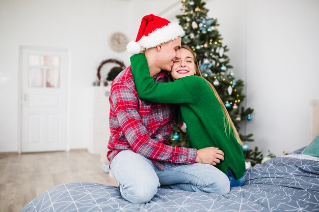 Couple hugging on bed at christmas