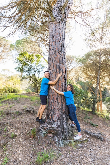 Free photo couple hugging tree in beautiful forest