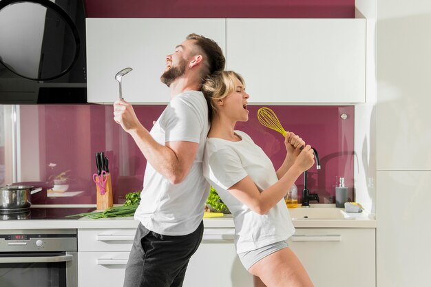 Couple indoors singing in the kitchen front view