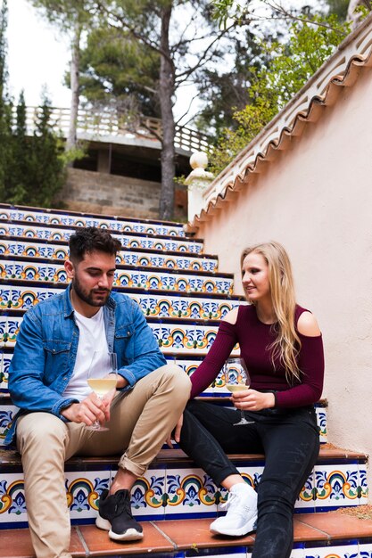 Couple interacting while having drinks on staircase