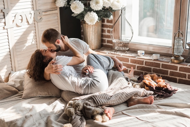 Couple kissing each other on messy bed