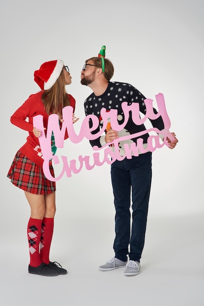 Free Photo couple kissing and holding a christmas banner