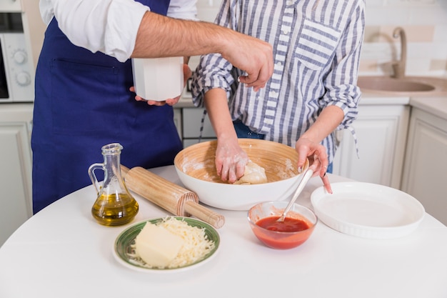 Couple kneading dough for pizza in bowl 