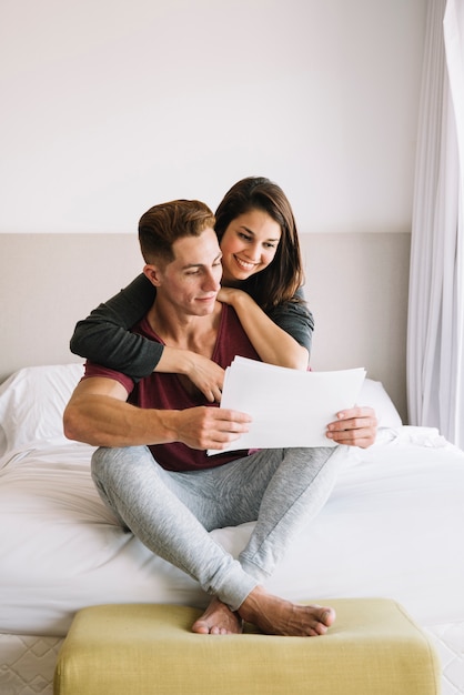 Couple looking at papers on bed