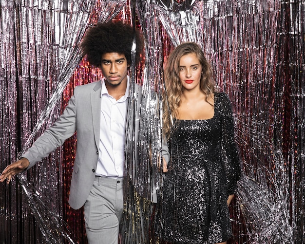 Free photo couple looking straight from curtain of sparkles