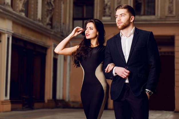 Free photo couple in love in   elegant outfit walking in old town street . pretty brunette woman with red lips and her handsome boyfriend have time off.