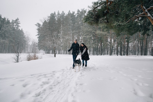 Couple in love have fun with Husky dog in snowy winter cold day