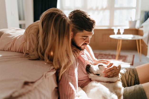 Couple in love looks at lying and sleeping Labrador. Husband and wife relax in cozy atmosphere.