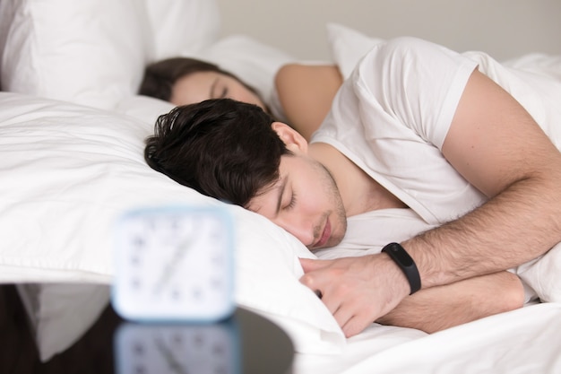 Free photo couple lying asleep in bed, man wearing wristband smart watch