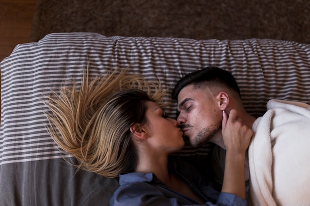 Free photo couple lying on bed kissing each other