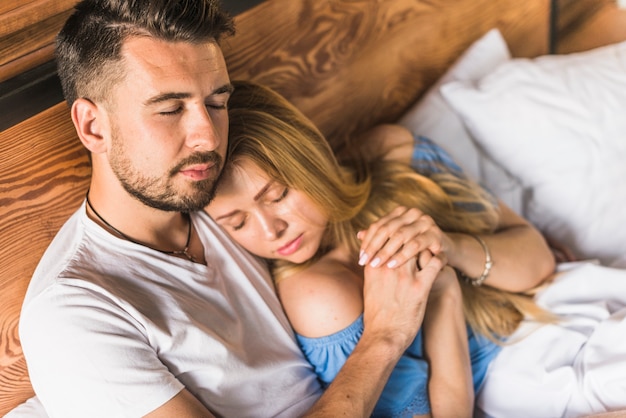 Free photo couple lying on bed with eyes closed