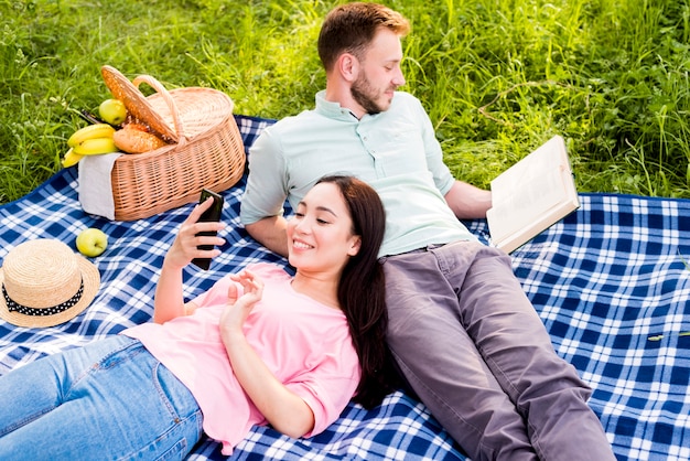 Free photo couple lying on picnic plaid and relaxing