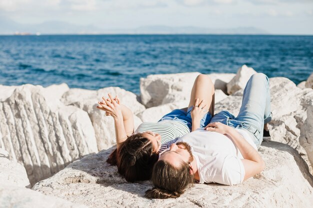 Couple lying on rocks by the sea