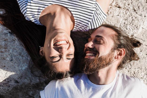 Free photo couple lying on rocks at the sea