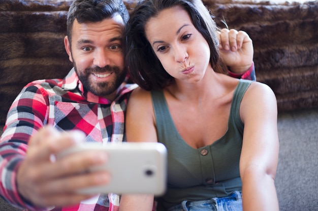 Couple making funny expression while taking selfie on cellphone