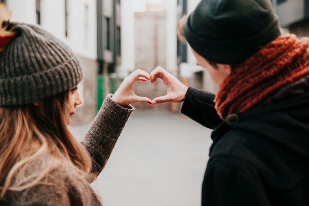 Free Photo couple making hand heart gesture