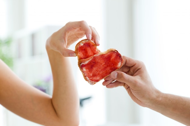 Free Photo couple making heart sign with two slices of bread with jam.