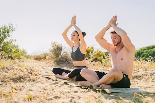 Free photo couple meditating together at the beach