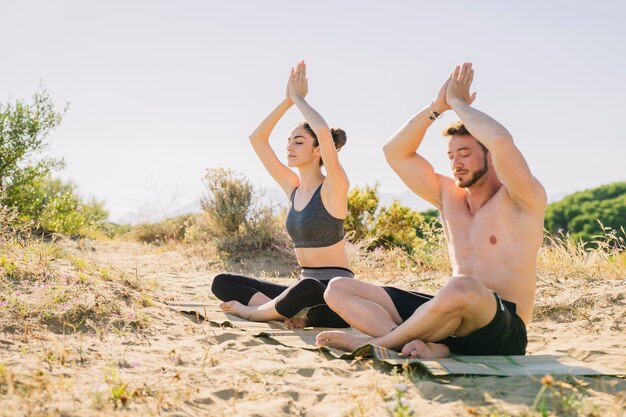 Couple meditating together at the beach