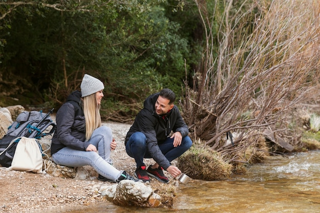 Couple in nature drinking water from river