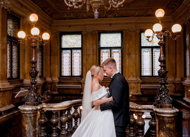 Free photo couple of newlyweds hugging in luxury hall of castle