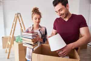 Free photo couple packing books and lamp to the boxes