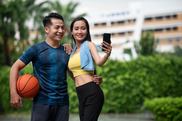 Couple posing together outdoors for a selfie with basketball