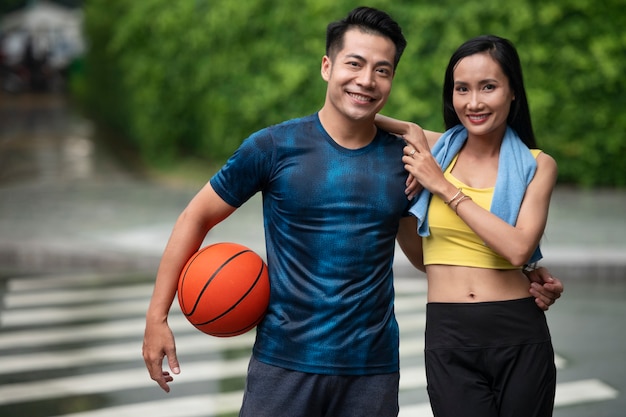 Couple posing together while outdoors with basketball