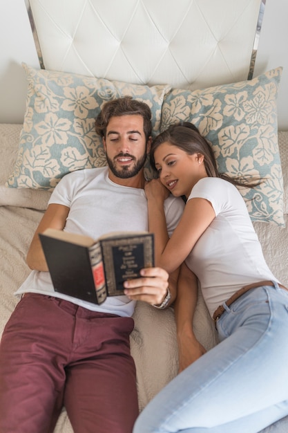 Couple reading book on bed together