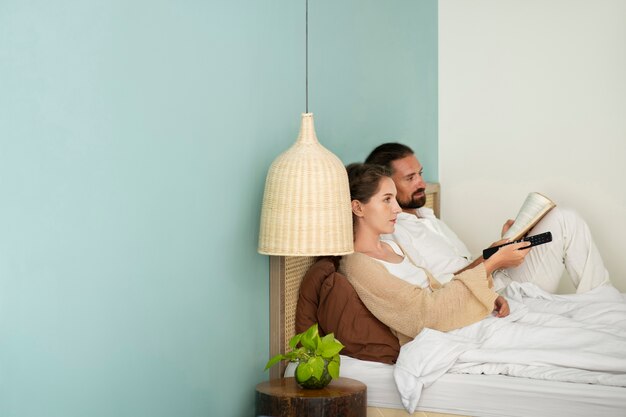 Couple reading a book and watching tv in their room during vacation