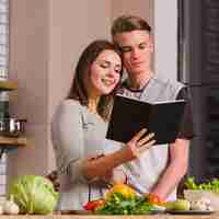 Free photo couple reading book while cooking together