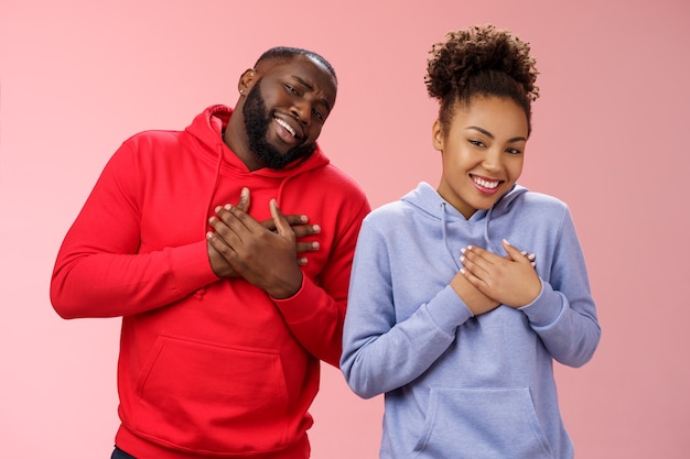 Free photo couple receive compliments look good together. portrait charming friendly loving african-american girlfriend boyfriend press palms heart touched pleased smiling broadly grateful moving words