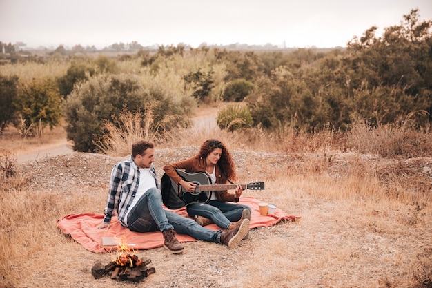 Couple relaxing outdoors next to a camp fire