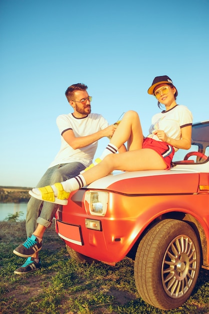 Free photo couple resting on the beach on a summer day near river. caucasian man and woman drinking beer