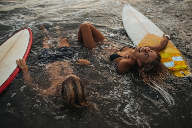 Free photo couple resting in water with surfboards