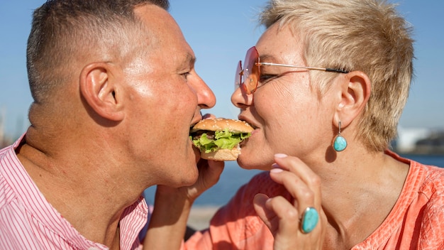 Free photo couple sharing a burger outdoors