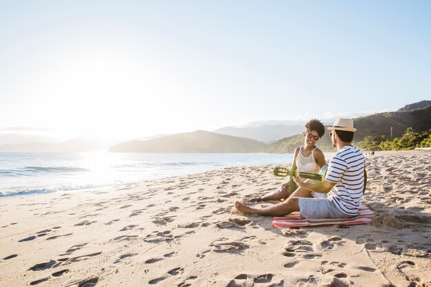 Couple sitting at the beach with guitar