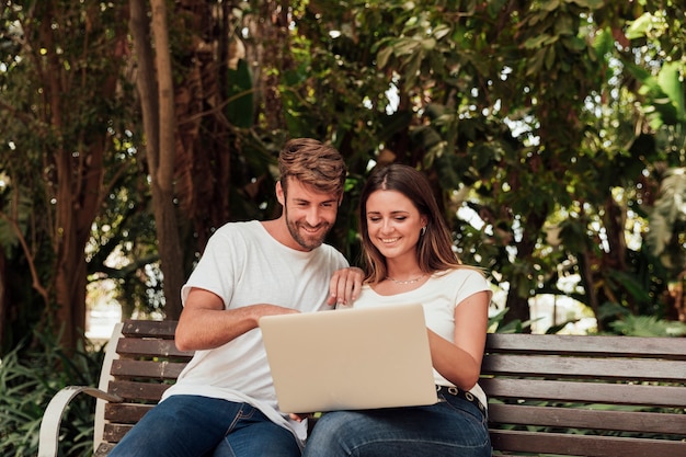 Couple sitting on a bench with laptop