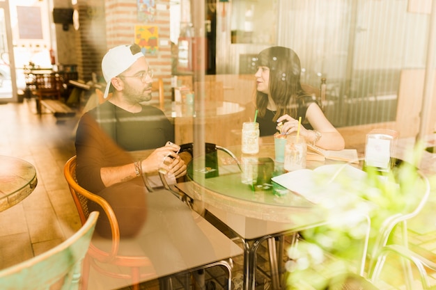 Free photo couple sitting in cafe seen from glass window